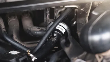 Mangueira de abastecimento GNV conectada a um carro adaptado para receber o combustível.