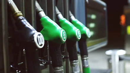 Mangueiras das bombas de combustíveis com sinalização verde e preta e conectadas a um tanque de combustível subterrâneo