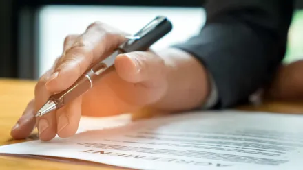 Homem segurando uma caneta e lendo um documento para simboilizar o entendimento do Certificado de Posto Revendedor da ANP