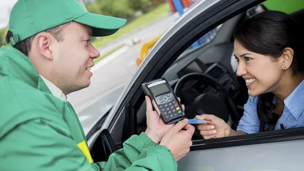 Vendedor segurando uma máquina de pagamento em cartão e seguindo um script de vendas para prestar um atendimento de qualidade ao cliente em um posto.