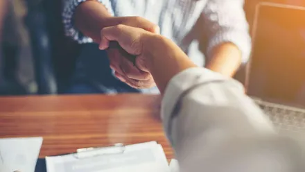 Dois empresários apertando as mãos para simbolizar a importância da parceria no comércio local.