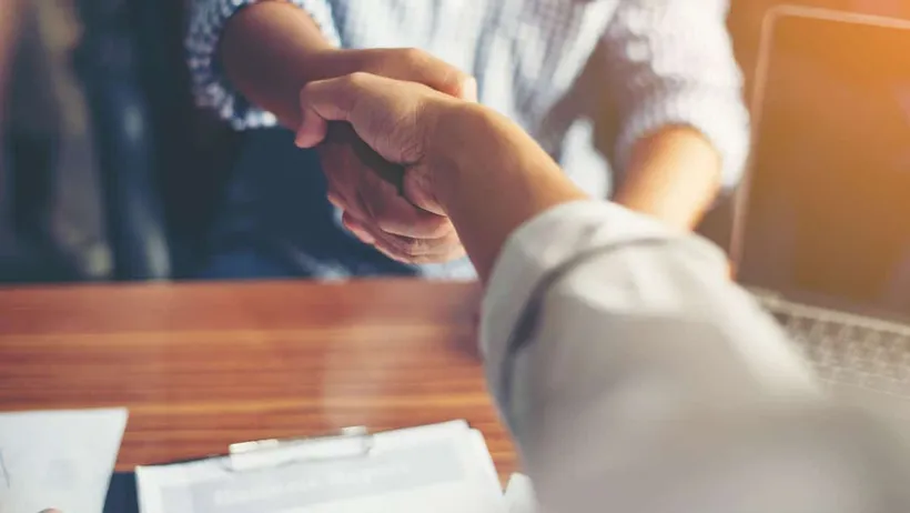 Dois empresários apertando as mãos para simbolizar a importância da parceria no comércio local.