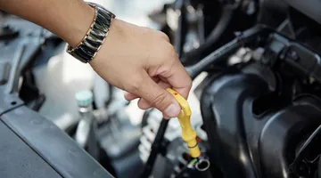 Técnico de lubrificação verificando o nível do produto em uma troca de óleo dentro do posto de combustível.