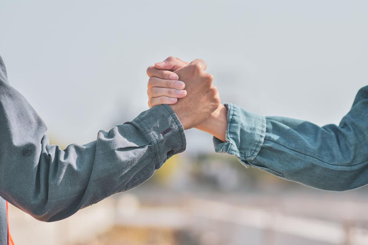 Dois homens apertando as mãos em um fundo borrado para simbolizar um programa de fidelidade e parceria.