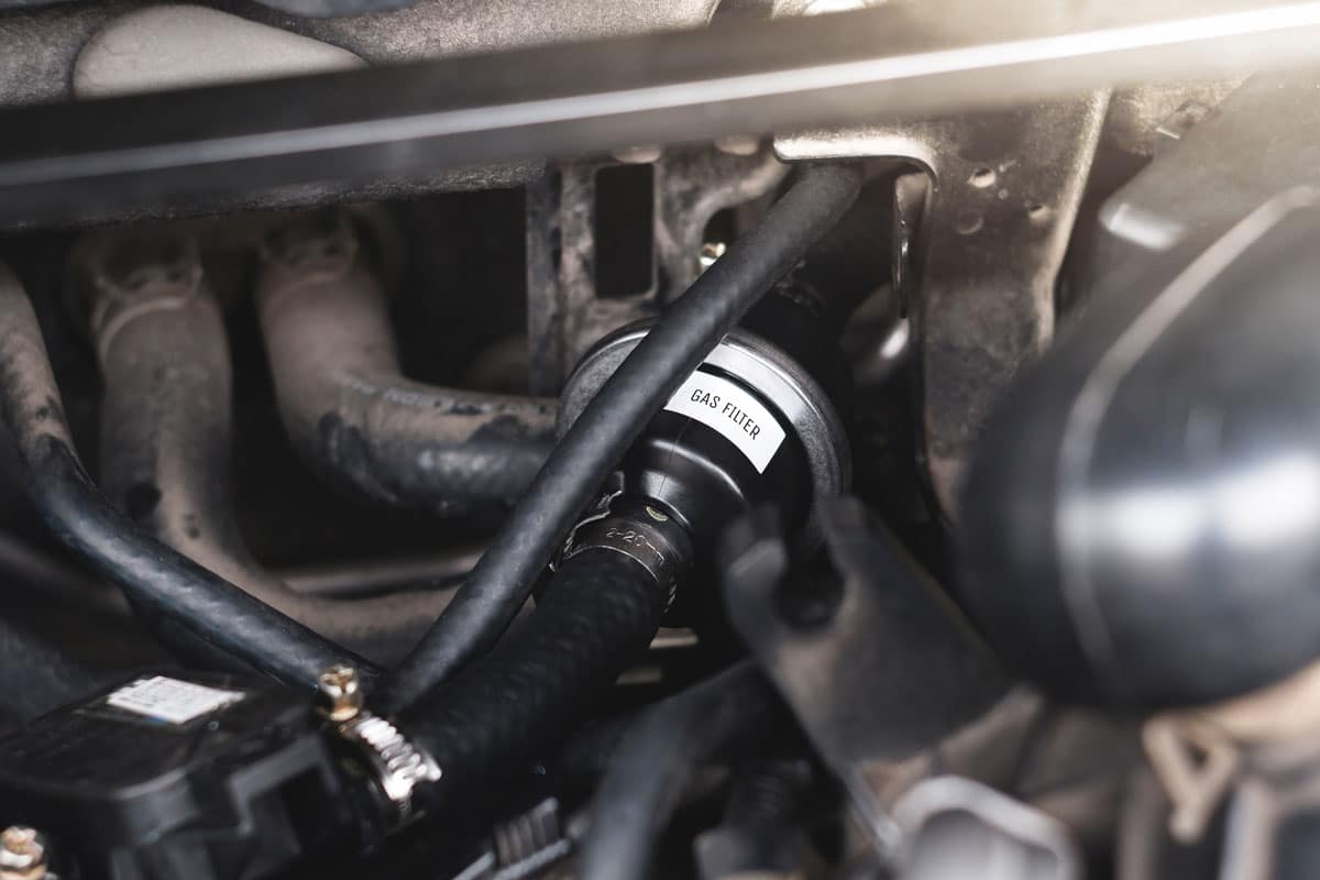 Mangueira de abastecimento GNV conectada a um carro adaptado para receber o combustível.