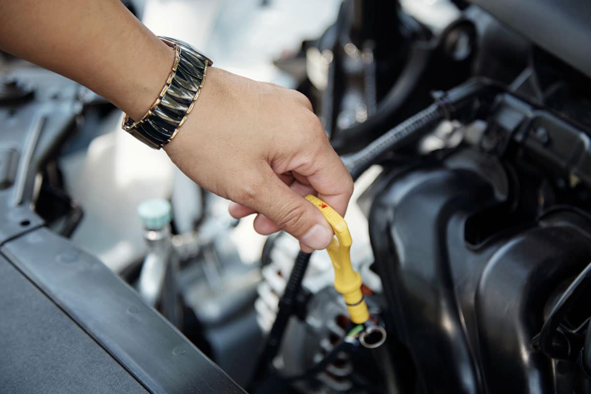 Técnico de lubrificação verificando o nível do produto em uma troca de óleo dentro do posto de combustível.